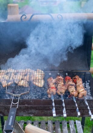 Backyard barbecue grill with skewers and grilled food on a summer day