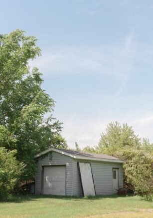 White wooden backyard storage shed under a clear blue sky